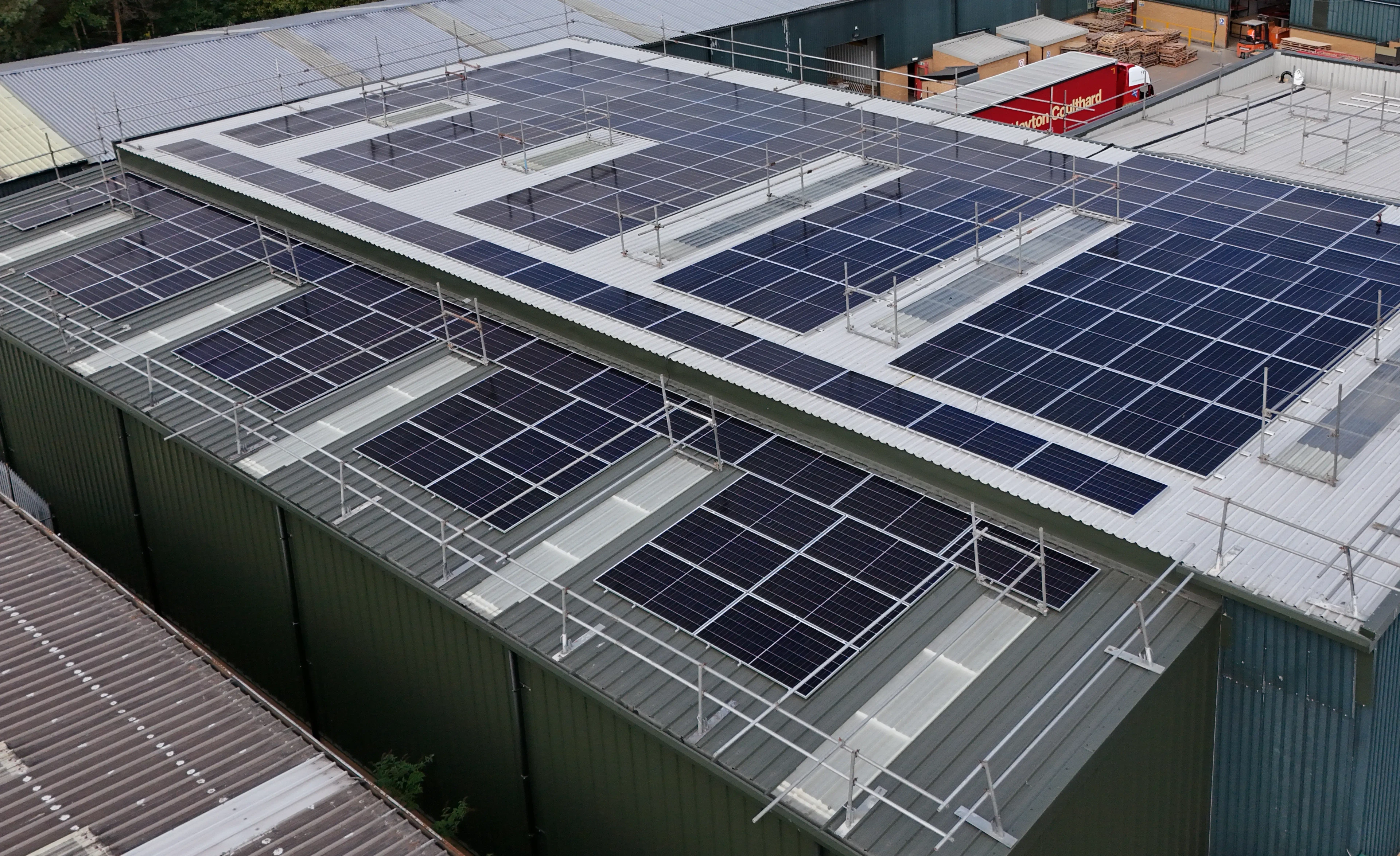 Aerial view of large-scale commercial solar panel installation across industrial rooftops