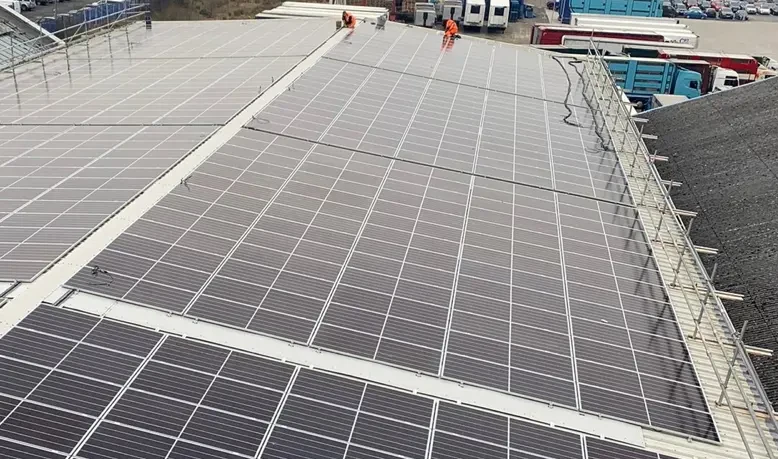 Aerial view of large factory roof covered in solar panels
